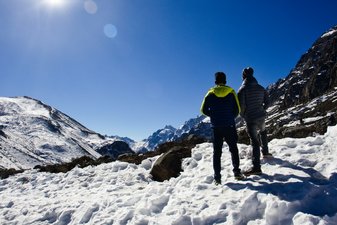 man in yellow and black jacket standing on snow covered ground during daytime